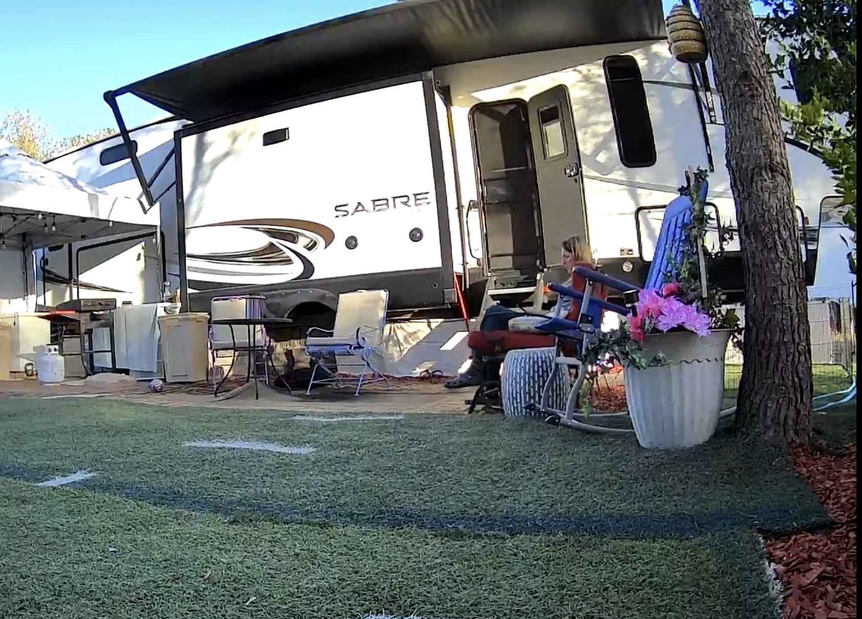 make your home special for grandchildren. Fenced grassy yard with potted fruit trees and a slide behind a fifth wheel RV