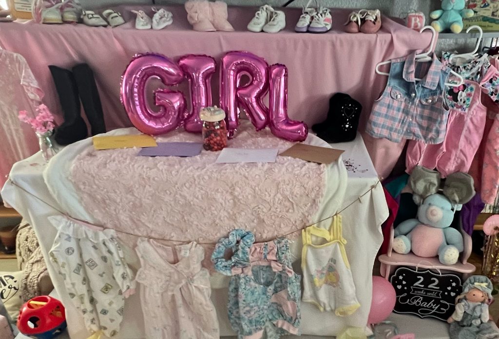 A display of my daughter's childhood clothes and toys, kept over twenty years at her baby shower. keeping a journal for your grandchild